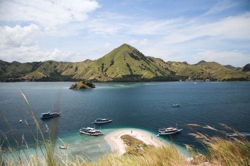 Free Explore the breathtaking beauty of Komodo Island with boats and lush mountains under a clear sky. Stock Photo