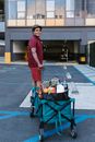 Man in Yellow Polo Shirt and Blue Denim Jeans Holding a Black and Red Cart With on on on on