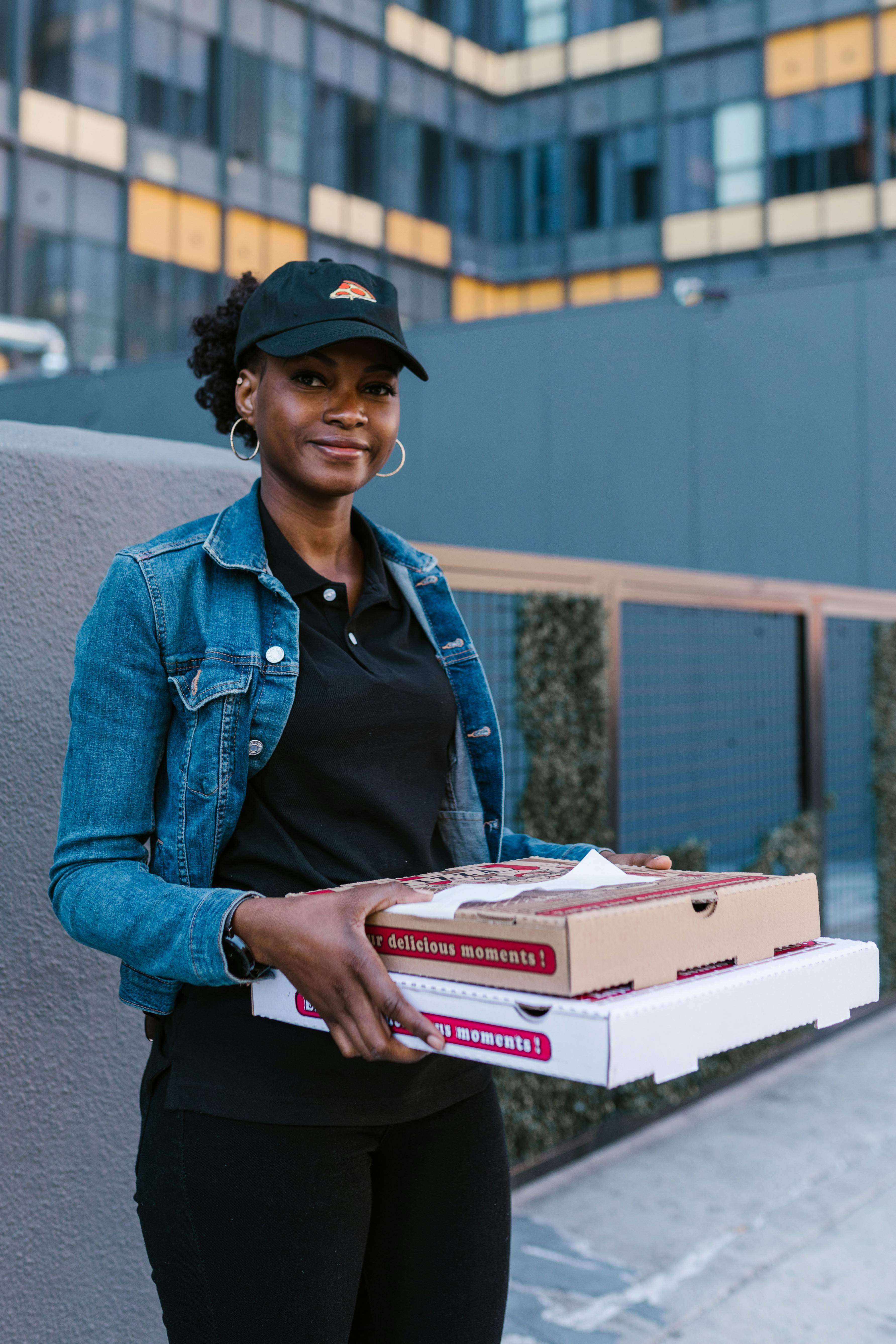 a woman in denim jacket delivering pizza