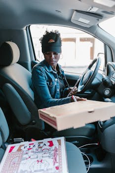 Woman in a car preparing to deliver pizza with a clipboard. Perfect for delivery and career themes.