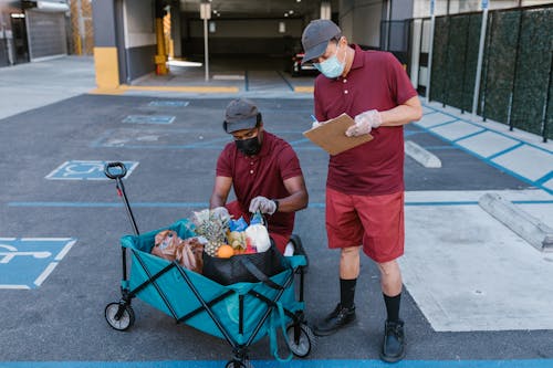 Man in Red Crew Neck T-shirt and Black Pants Holding Black and Gray Stroller