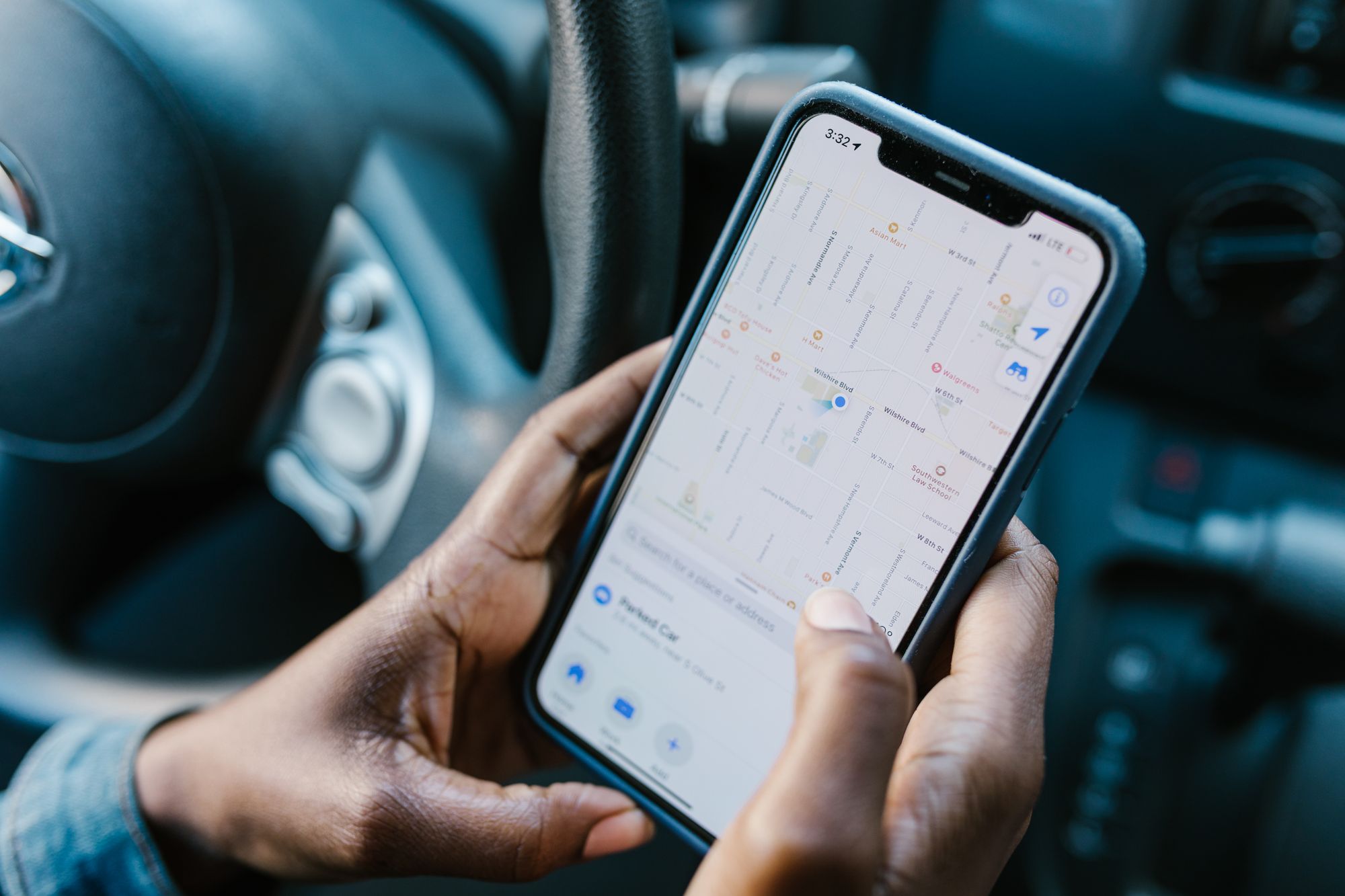 Shows a person using a smartphone map app inside a car, directly matching the advice to use apps like PlugShare before…