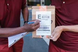 Kurir memeriksa paket pengiriman produk UMKM — courier checking UMKM product delivery packages