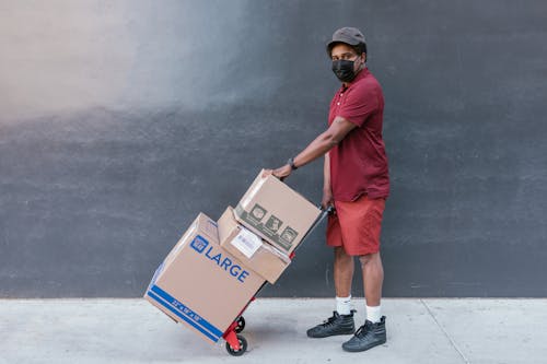 Man Holding a Trolley Push Cart with Cardboard Boxes