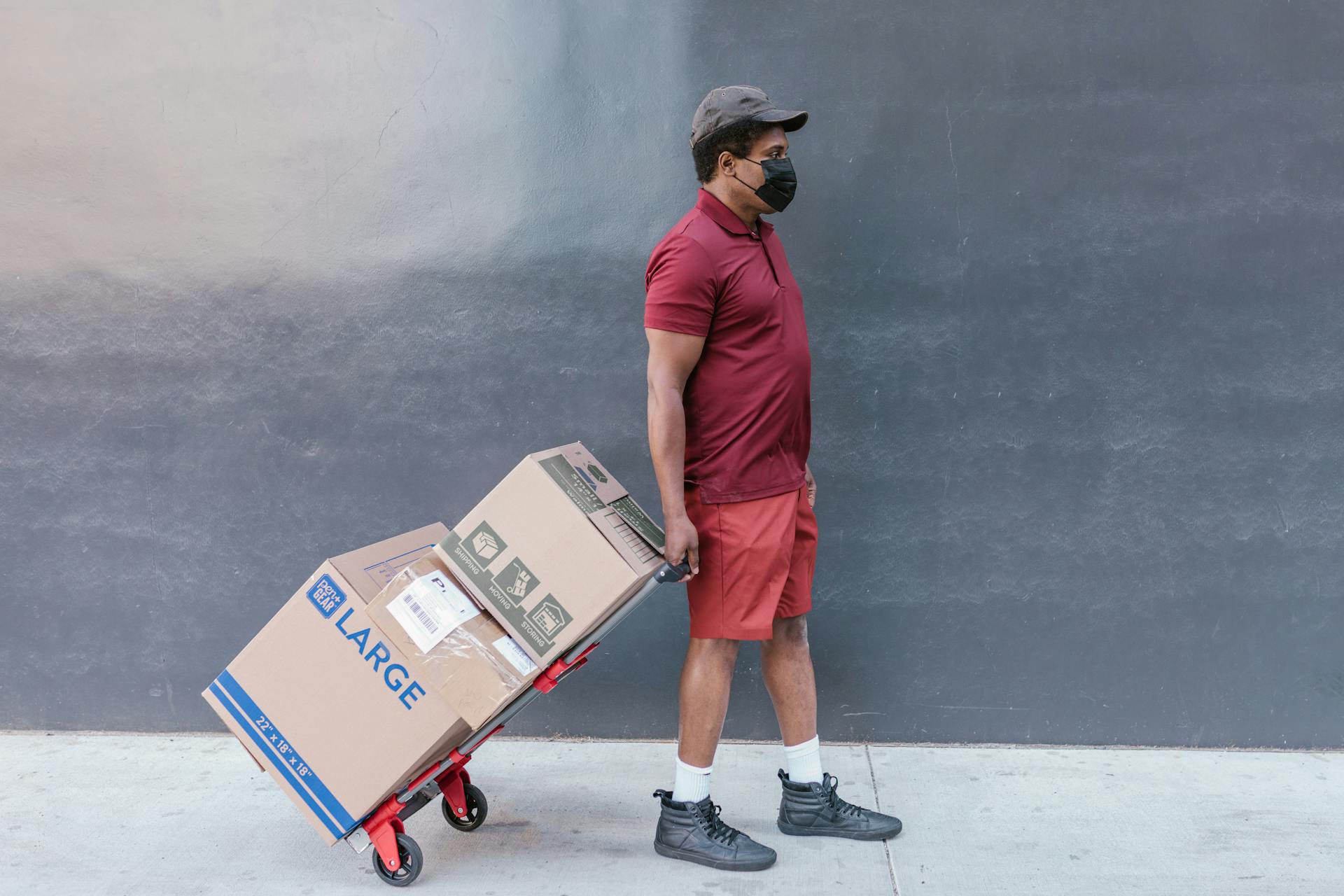 Man in Red Polo Shirt Pulling the Trolley Push Cart with Cardboard Boxes