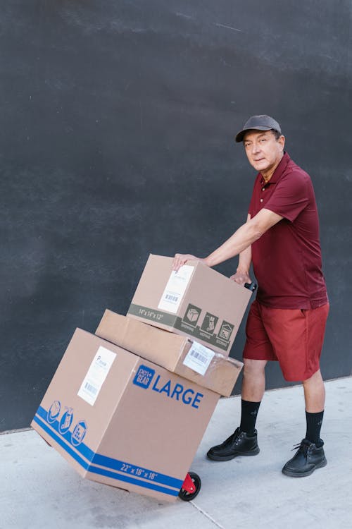 Adult Man Holding his Trolley Push Cart and Shipping Boxes