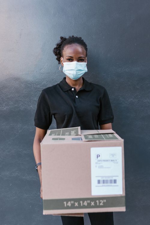 Woman Wearing a Face Mask While Holding a Box · Free Stock Photo