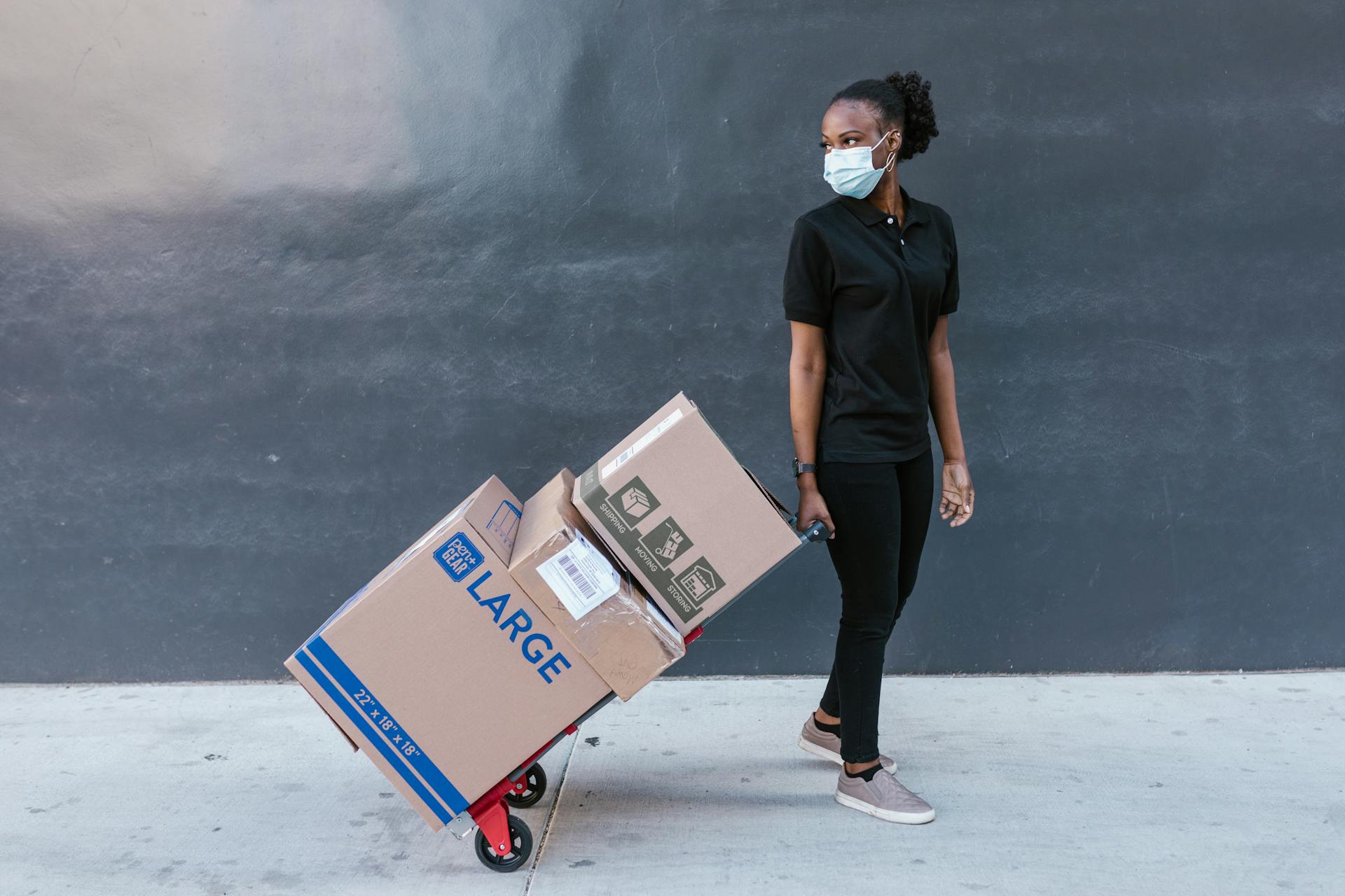 Woman in Black Polo Shirt Pulling the Trolley Push Cart with Shipping Boxes