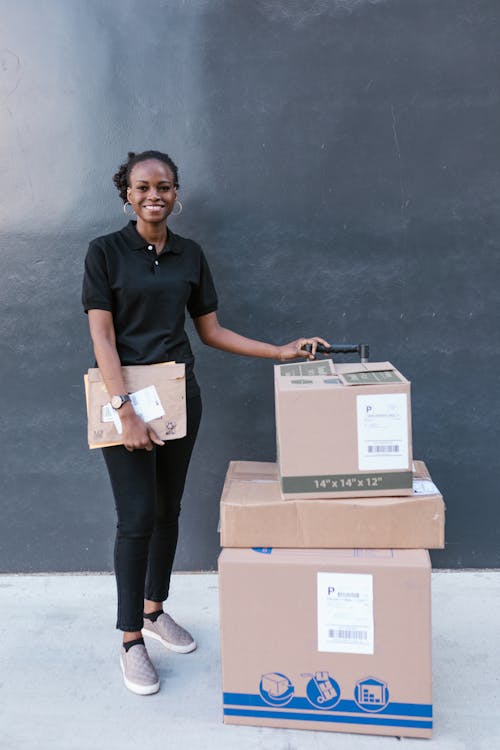 Woman Standing Next To Stack of Shipping Boxes 