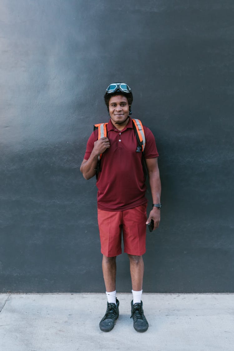 A Man In Maroon Shirt Carrying A Delivery Bag