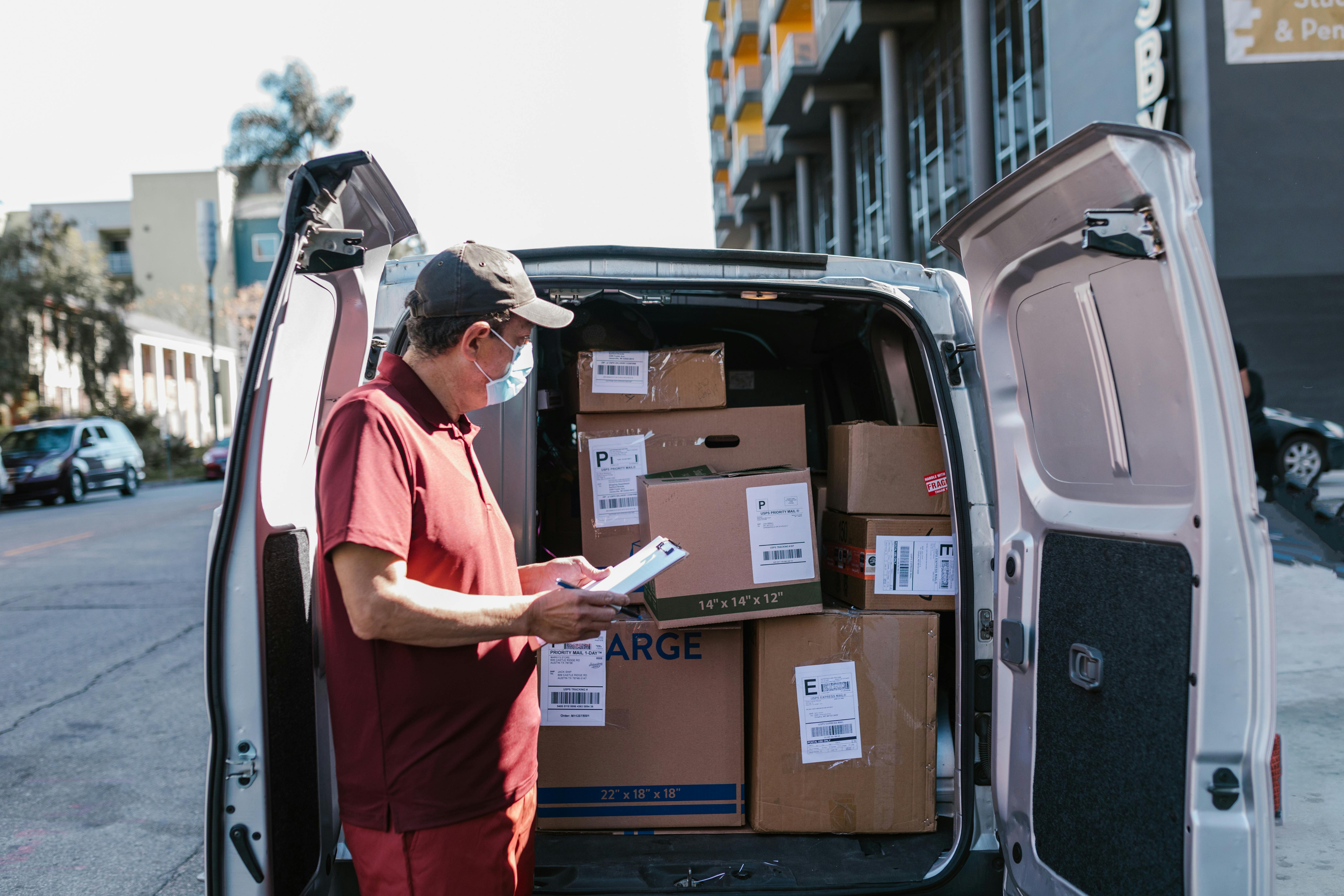 man standing checking the shipping boxes inside the van