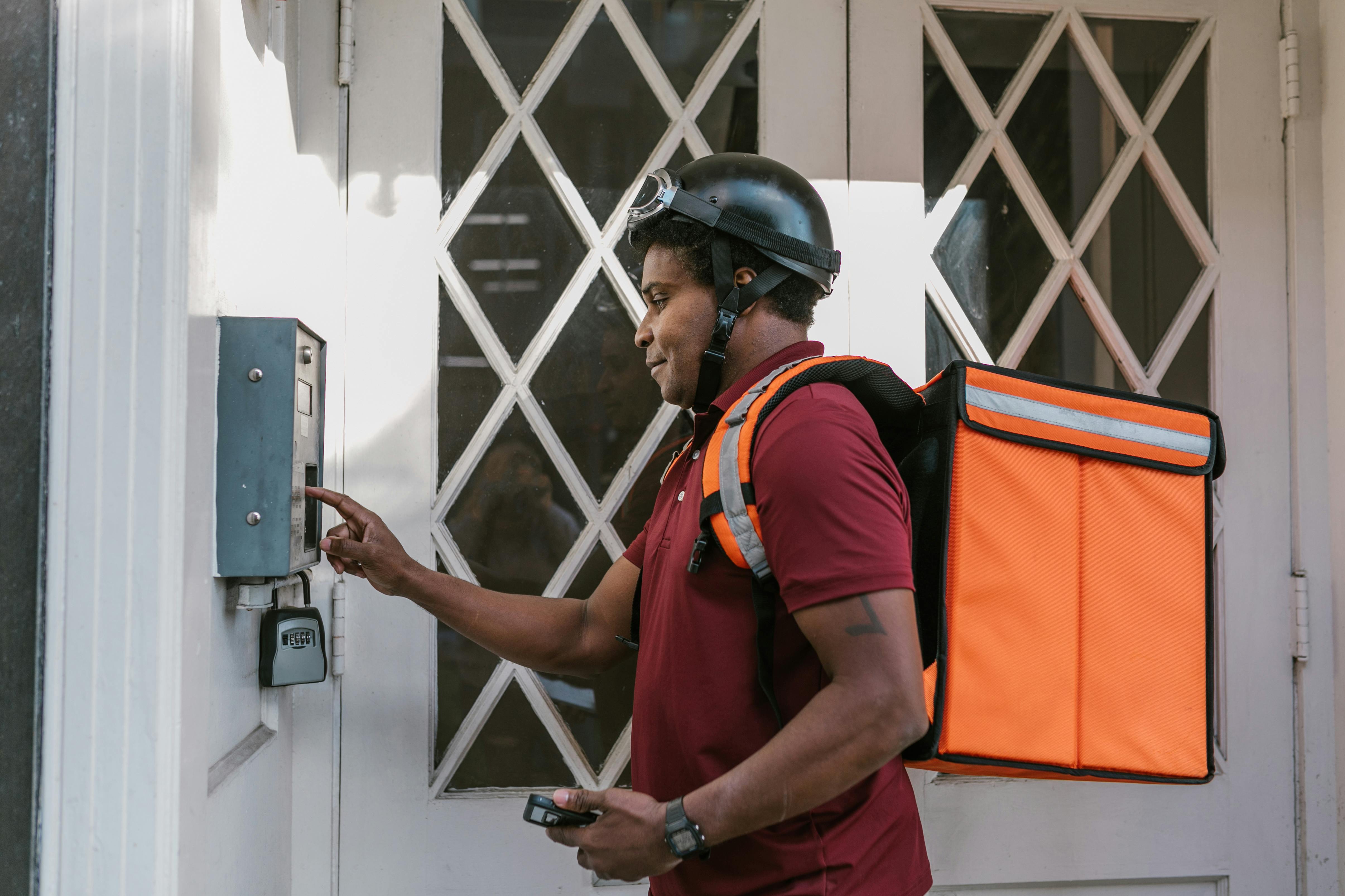 man in blue and orange polo shirt wearing black helmet holding gray metal box