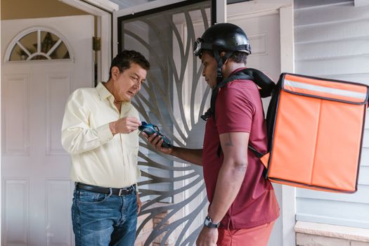 Delivery driver collects payment using card reader at customer's door.