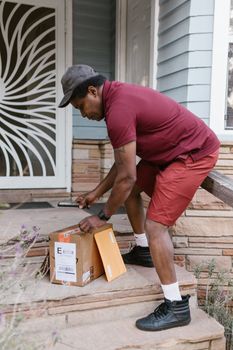 A deliveryman in uniform delivering parcels to a home doorstep during the day.