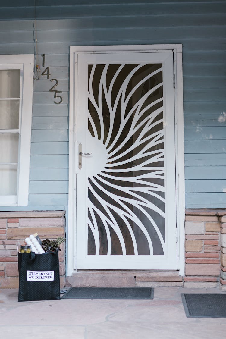 A Bag With Groceries Near A White Door