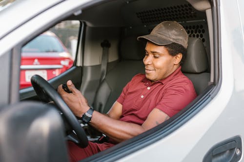Free Man in Red Polo Shirt and Brown Hat Driving Car Stock Photo