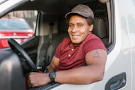 Smiling Man in Red Polo Shirt and Brown Cap Sitting inside a Vehicle