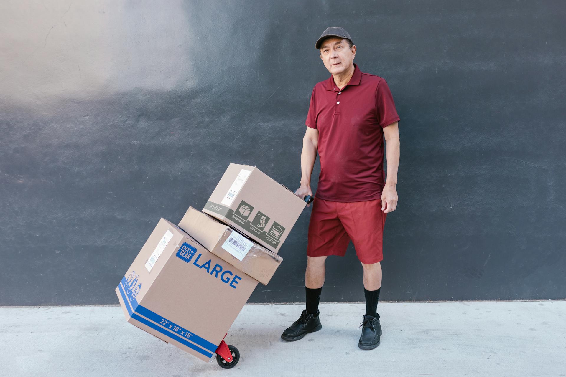 Man in Red Polo Shirt Pulling the Trolley Push Cart with Shipping Boxes