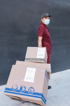Man in Red Long Sleeve Shirt Standing Beside Brown Cardboard Box