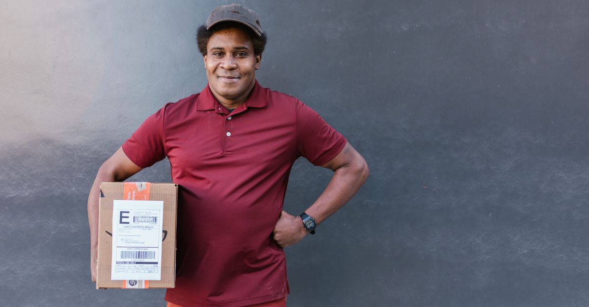 person holding a delivery package while standing next to a car