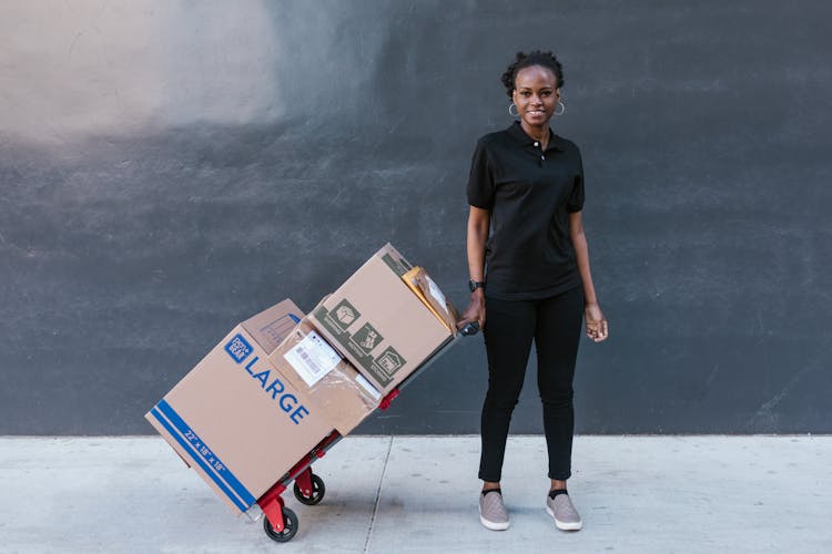 A Woman In Black Polo Shirt Pulling Delivery Boxes