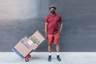 Man in Red Crew Neck T-shirt and Orange Shorts Holding Brown Cardboard Box