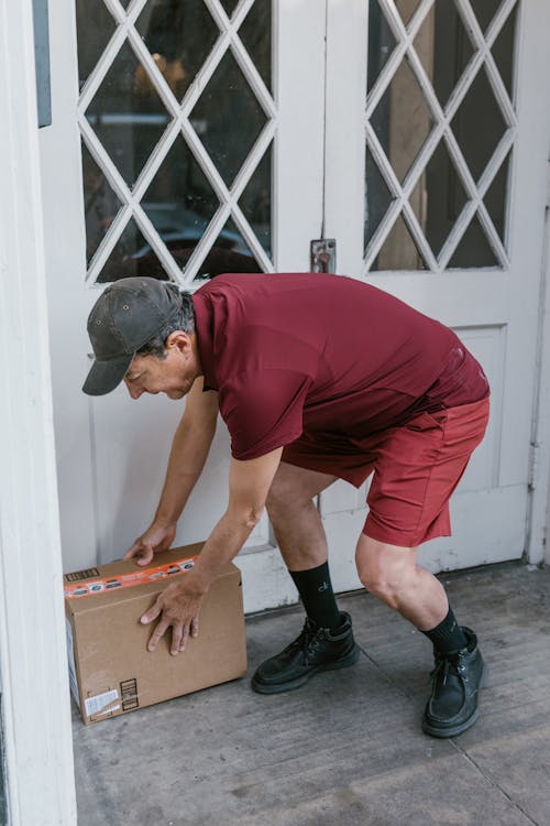 Free An Elderly Man Leaving a Package on the Front Door Stock Photo