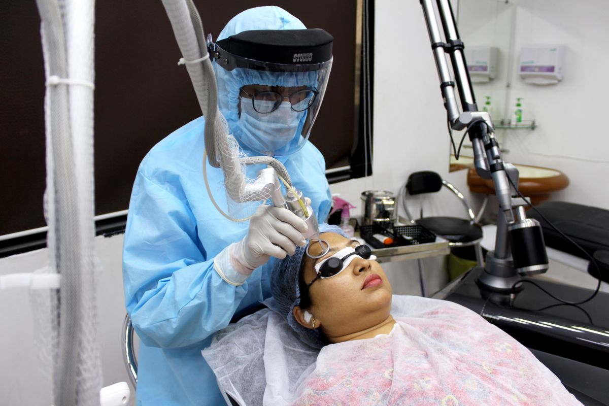 Doctor performing laser aesthetic facial treatment