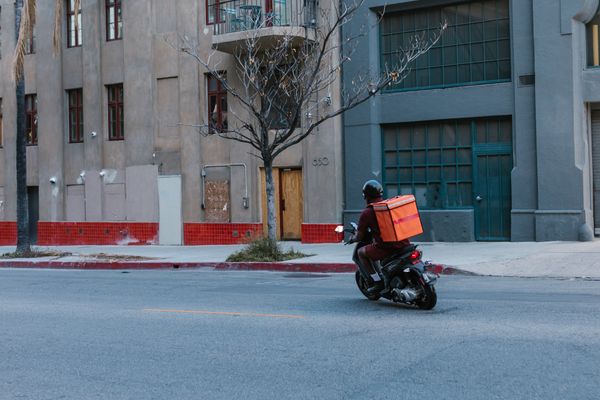 Courier riding scooter delivering package in city