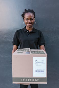 A cheerful delivery woman in a black uniform holds a package outdoors.