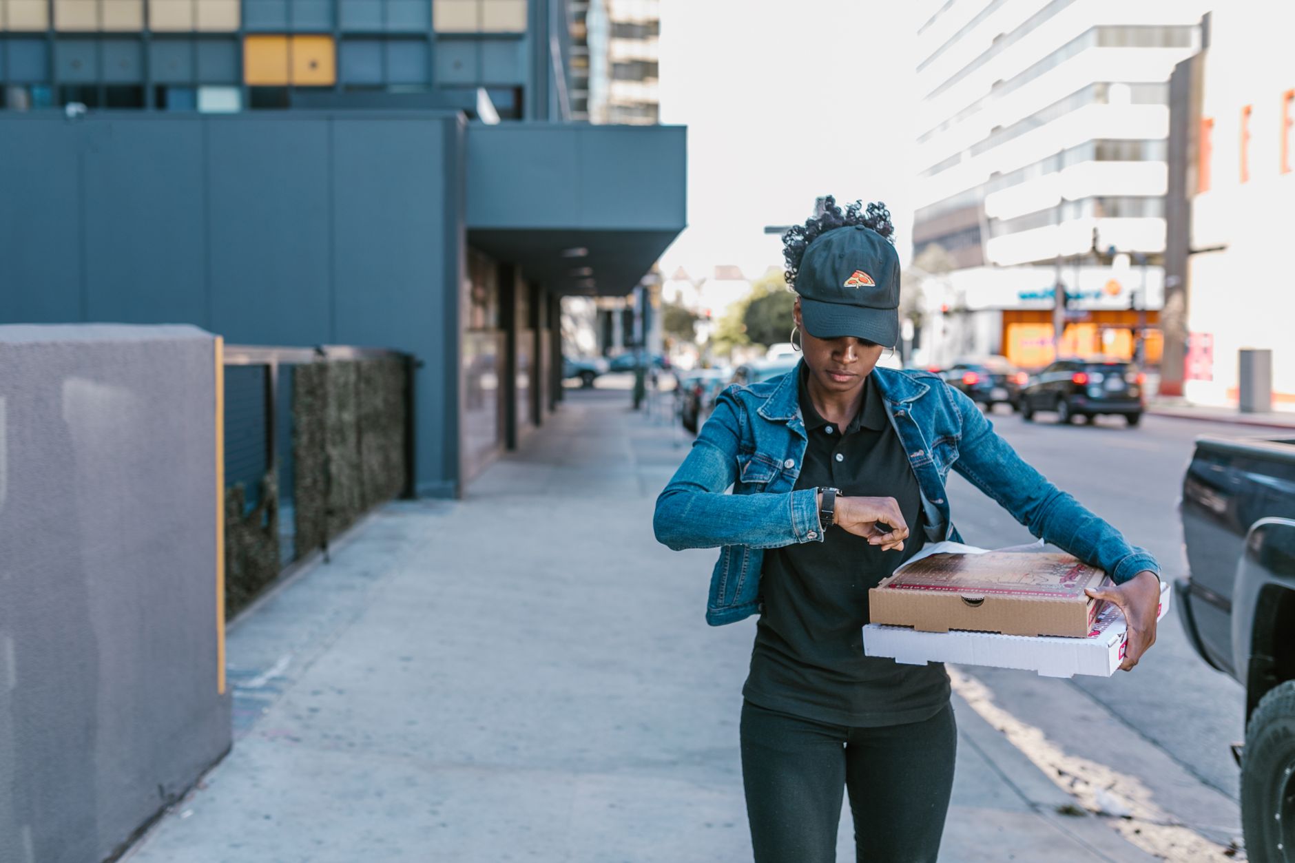 A woman delivering pizza boxes in an urban setting, showcasing city life and delivery service.