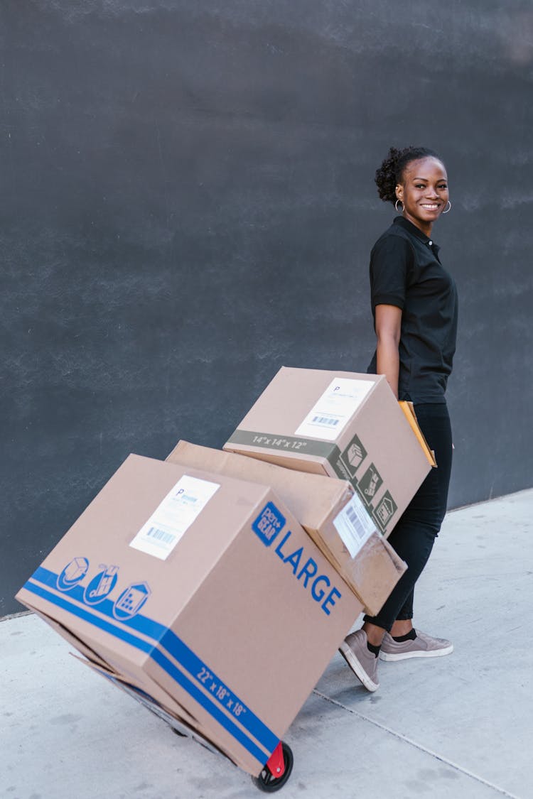 A Woman In Black Polo Shirt Pulling Delivery Boxes