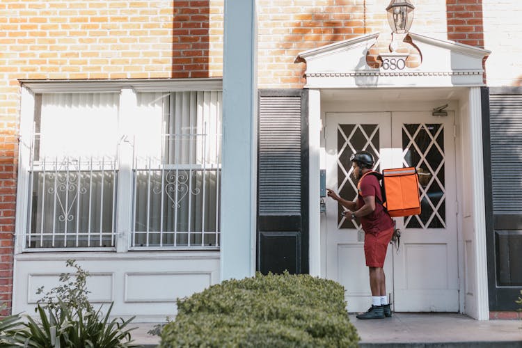 A Deliveryman Pressing The Doorbell