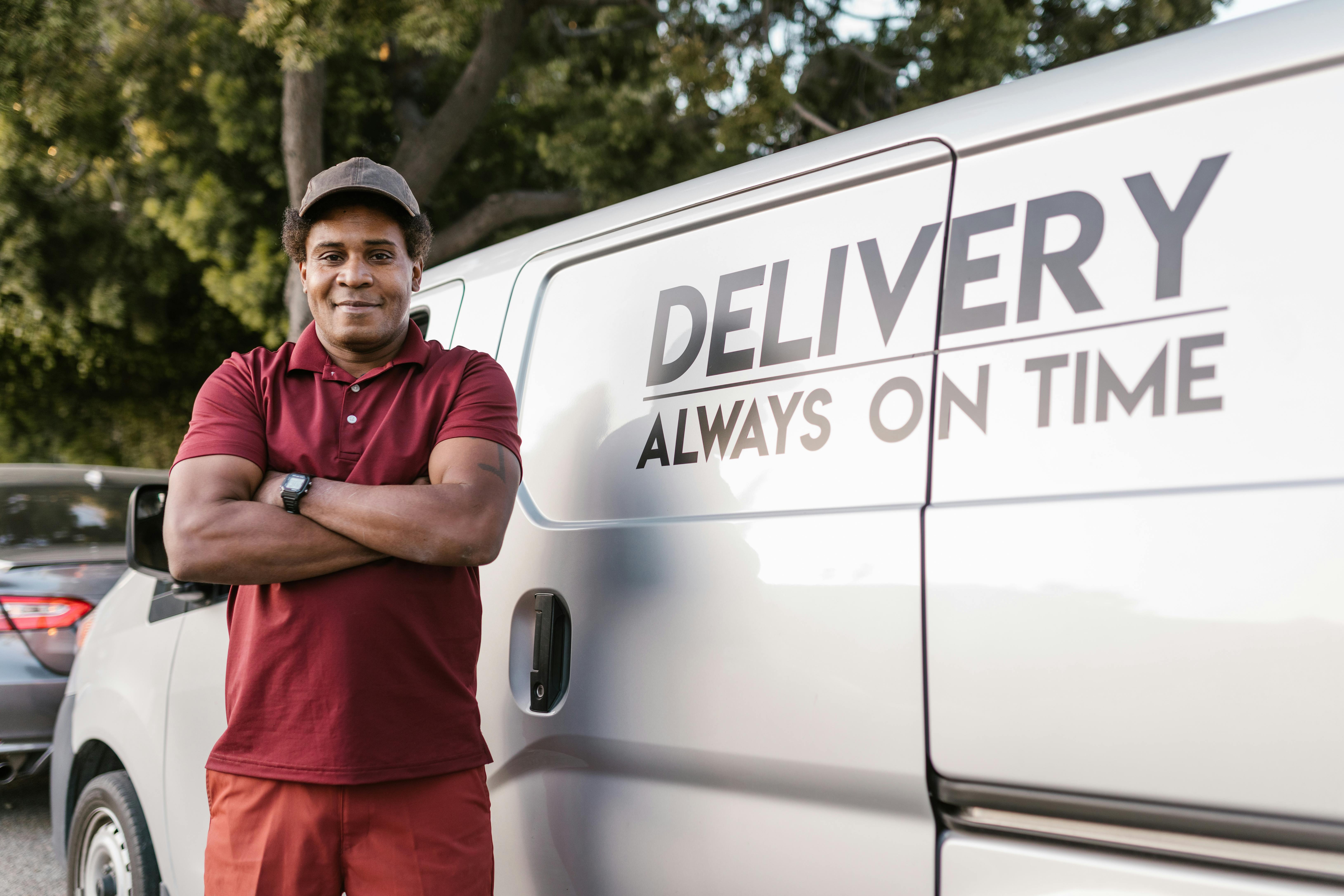 man in red and black polo shirt standing beside white van