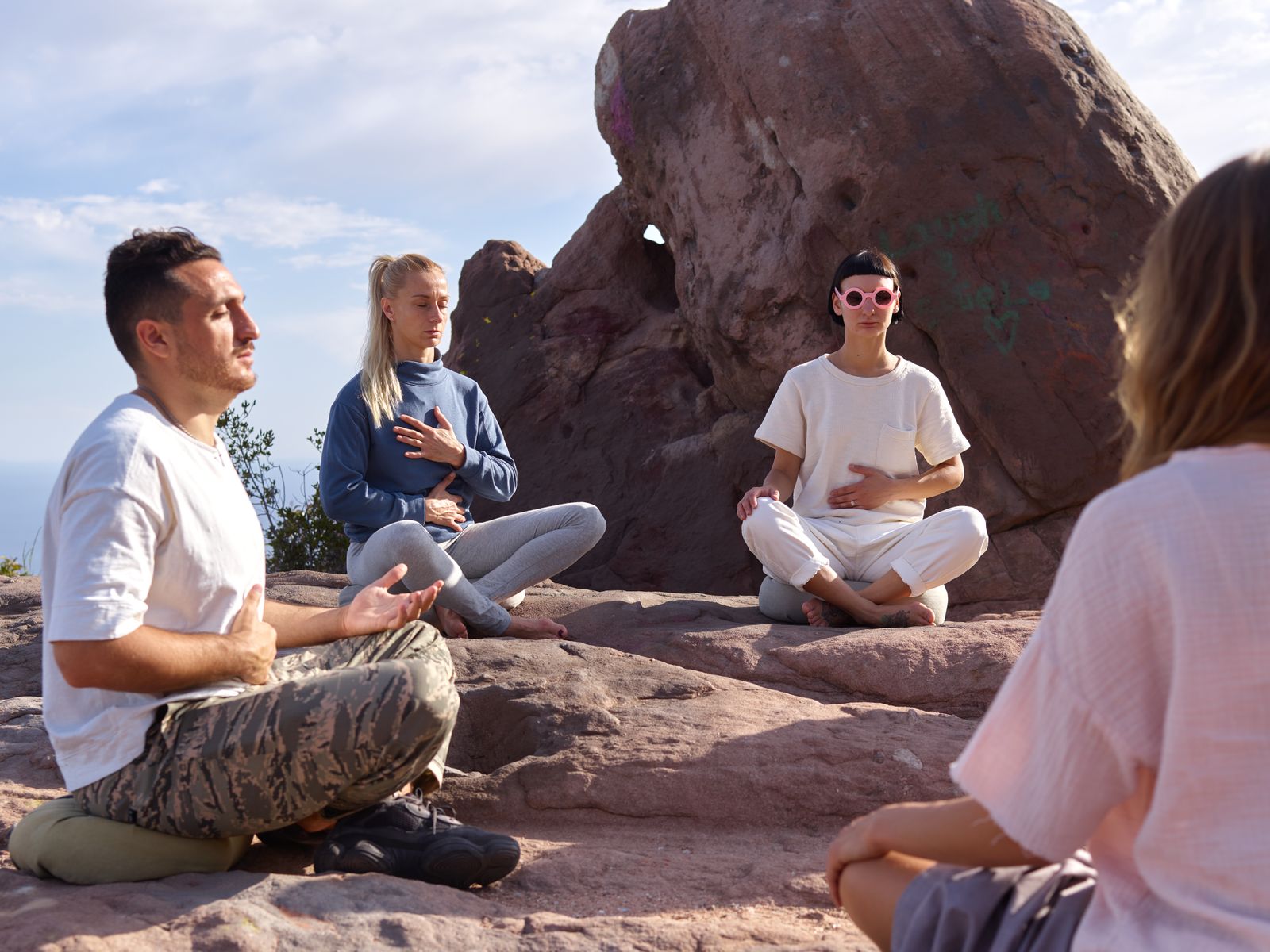 Four colleagues sitting on warm rock in a guided embodiment practice.