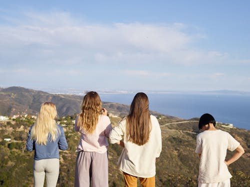 Group of People Standing and Looking at the Sea and Mountains 