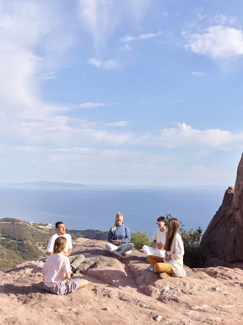 Free Group of People Sitting in Circle and Meditating on the Top of a Hill on the Seashore  Stock Photo
