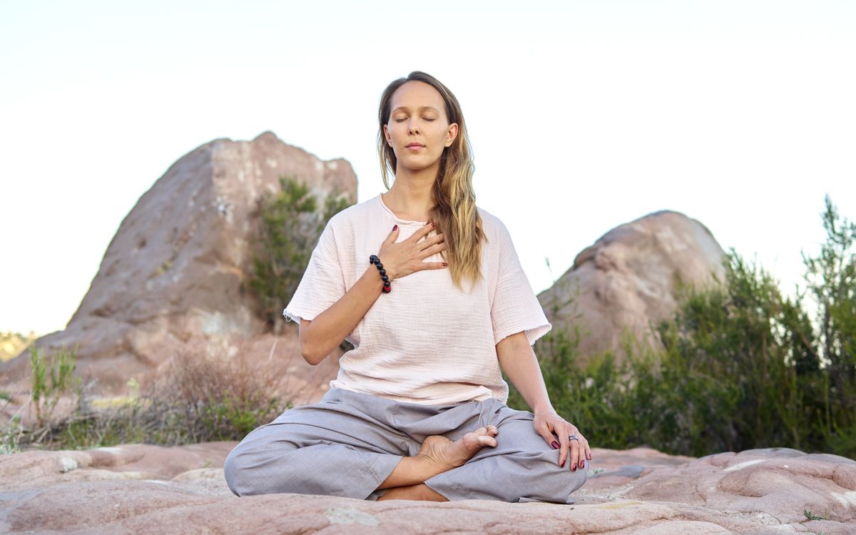 Woman meditating outdoors with closed eyes, embodying peace and relaxation.