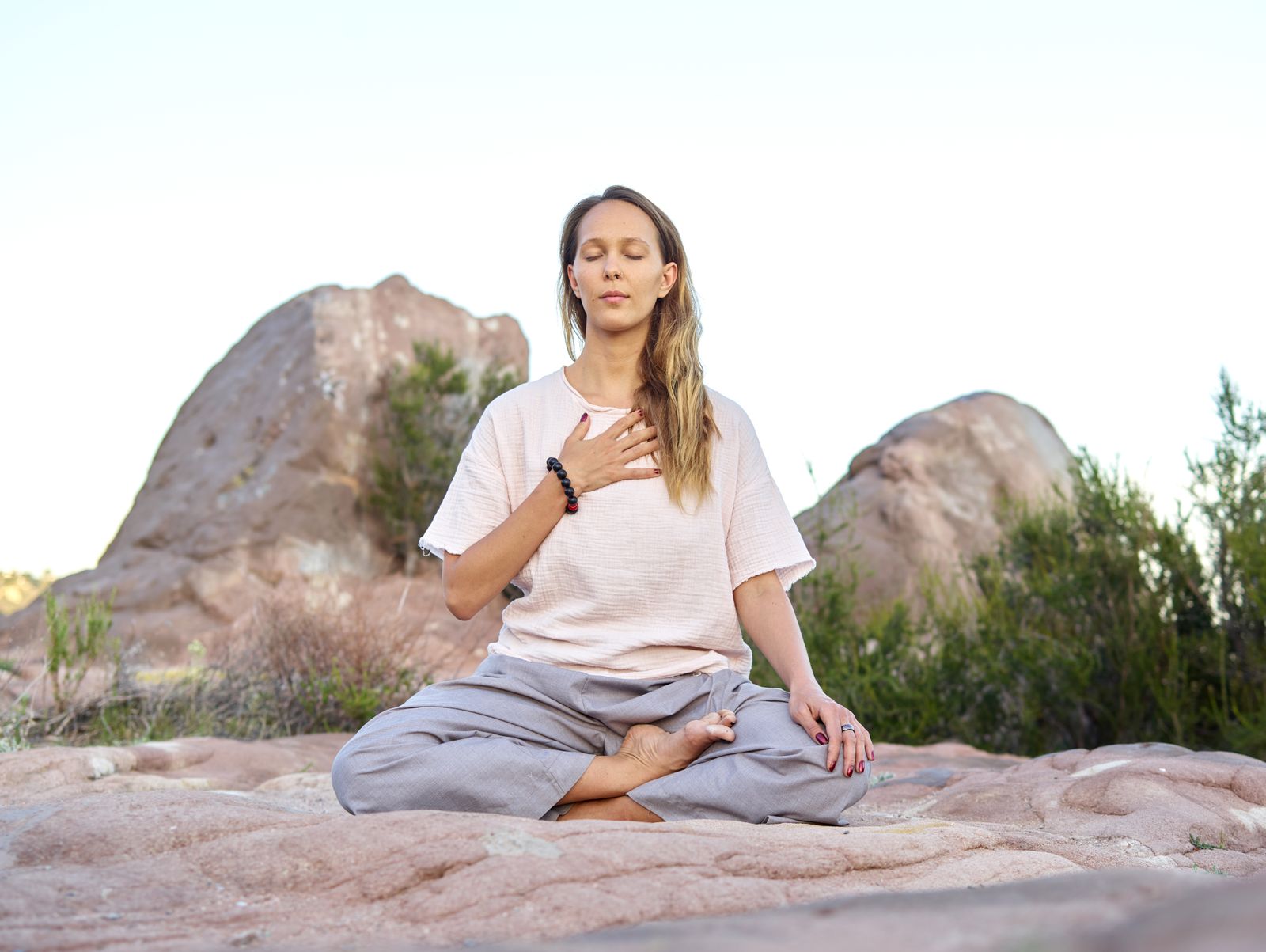 Woman meditating outdoors with eyes closed, grounding practice for the Muladhara root chakra