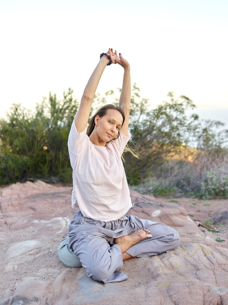 Woman Sitting On A Beach And Stretching Her Arms 