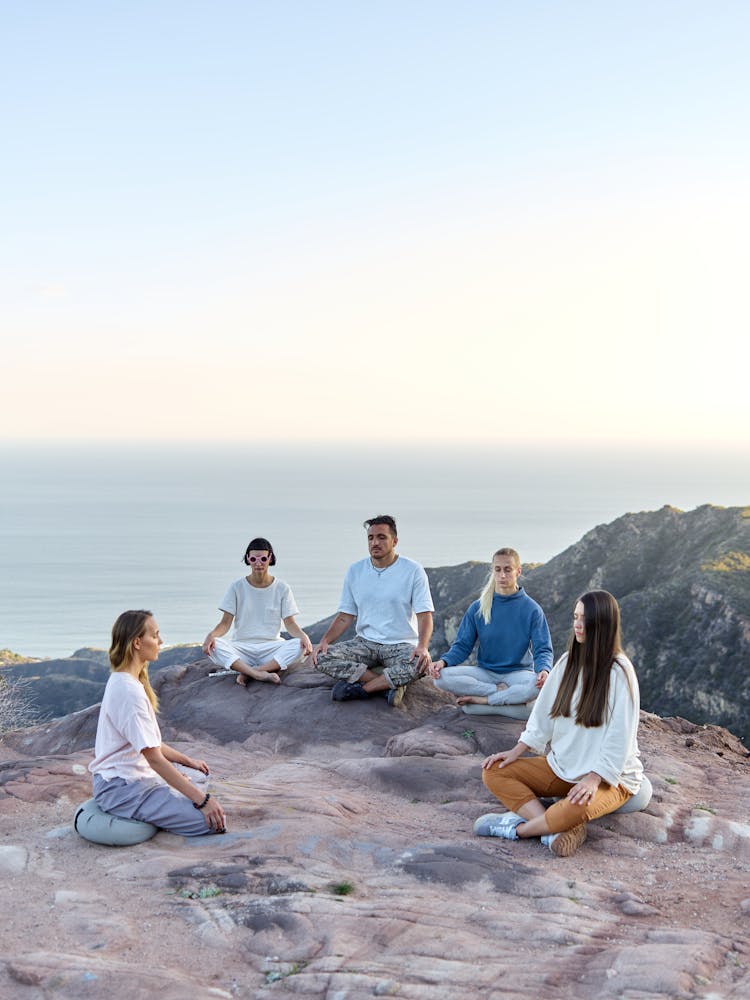 A Group Of People Meditating On A Beach