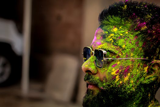 A colorful close-up of a man covered in Holi powder during a vibrant festival in Patna, India.