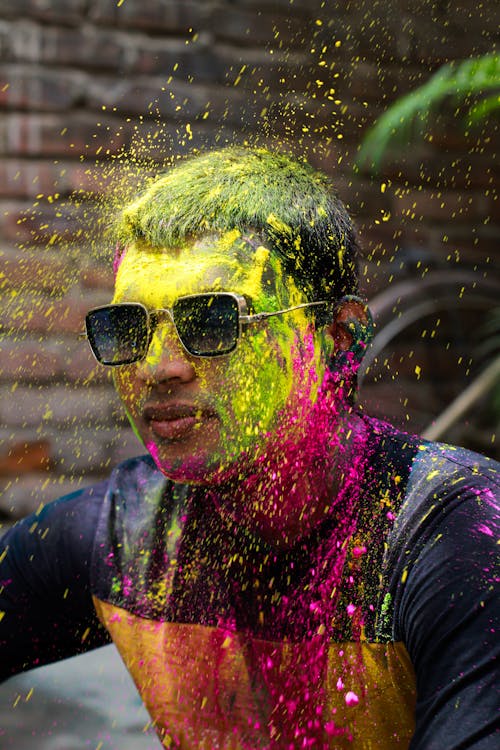 Man Wearing Sunglasses Covered in Colored Powders