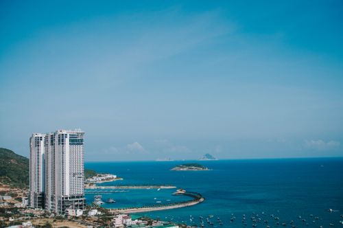Free Aerial view of Nha Trang coastline with skyscrapers, ocean, and boats under a clear blue sky. Stock Photo