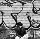 A Woman Sitting by a Wall with a Graffiti Art