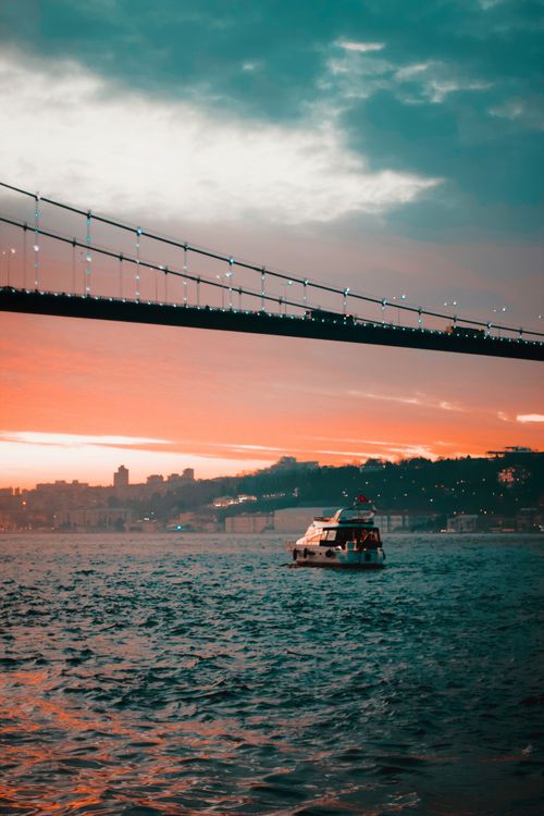 Free Scenic view of the Bosphorus Bridge and a boat at dusk in İstanbul, Türkiye. Stock Photo