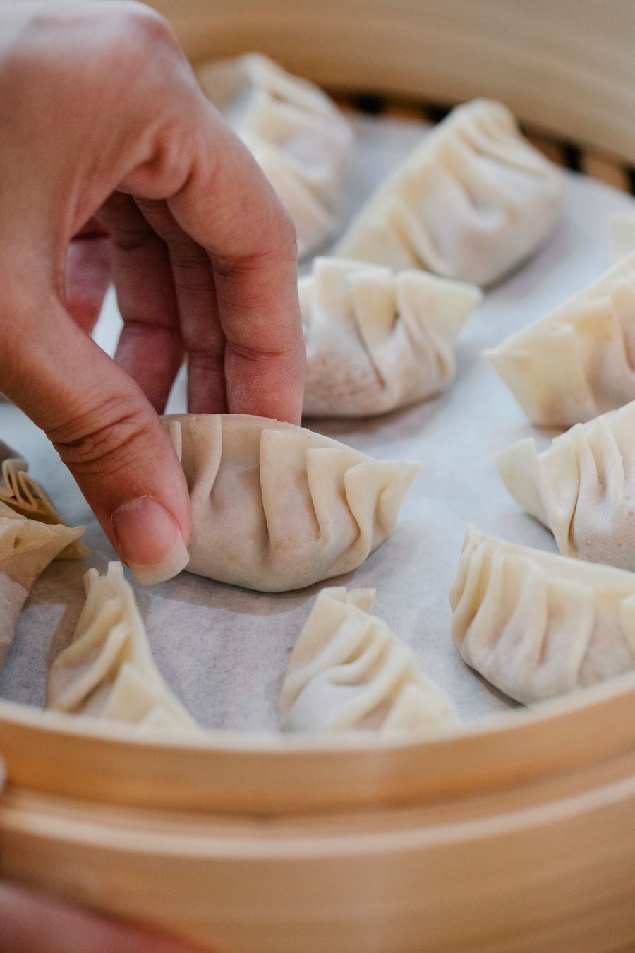 Tukang masak menyusun dim sum dalam kukusan bambu
