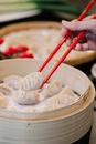 Crop woman with dim sum between chopsticks at home
