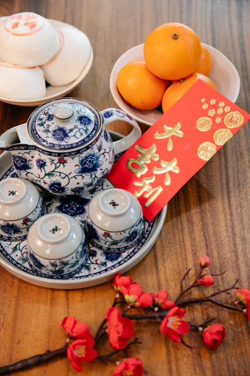 High angle of red packet with ornament in tray with oriental teapot and cups during New Year holiday