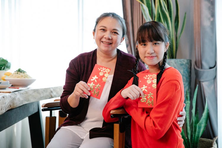 A Woman And A Girl Holding Red Envelopes